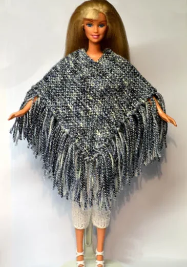 Barbie i grå stickad poncho med fransar och vita byxor.