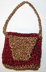 Röd stickad Barbie-väska med guldbrunt hålmönster och flätad rem.