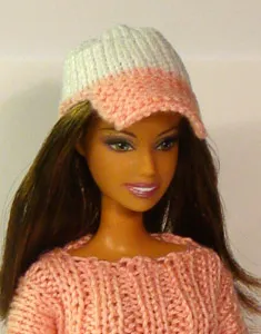 Barbie i rosa och vit stickad keps med bred skärm och matchande rosa tröja.