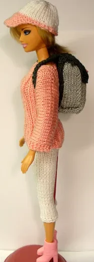 Barbie med grå stickad ryggsäck, rosa tröja och vit mössa.
