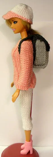 Barbie med grå stickad ryggsäck, rosa tröja och vit mössa.