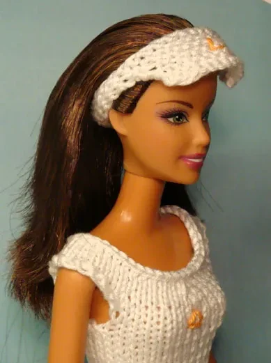 Barbie i vit stickad klänning med matchande pannband och orange detaljer.